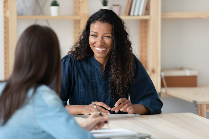 Two female colleagues chatting and smiling