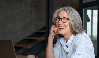 Woman laughing in front of a laptop